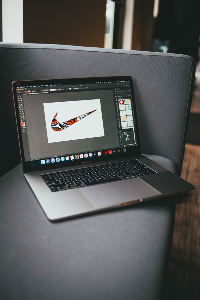 Vue plongeante d’un netbook moderne, avec un logiciel graphique ouvert, posé sur un canapé gris dans une pièce